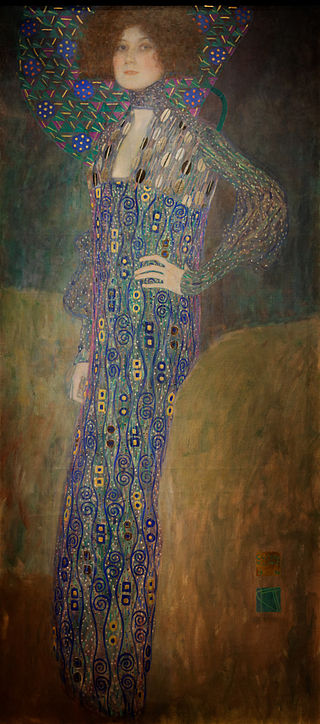 L'amante de Klimt regarde fièrement le spectateur, debout un poing sur la hanche. Elle est vêtue d'une longue robe bleue à motifs stylisés et se tient devant un fond très simple de noir et d'or, sur lequel se détachent quelques fleurs bleues géométriques.