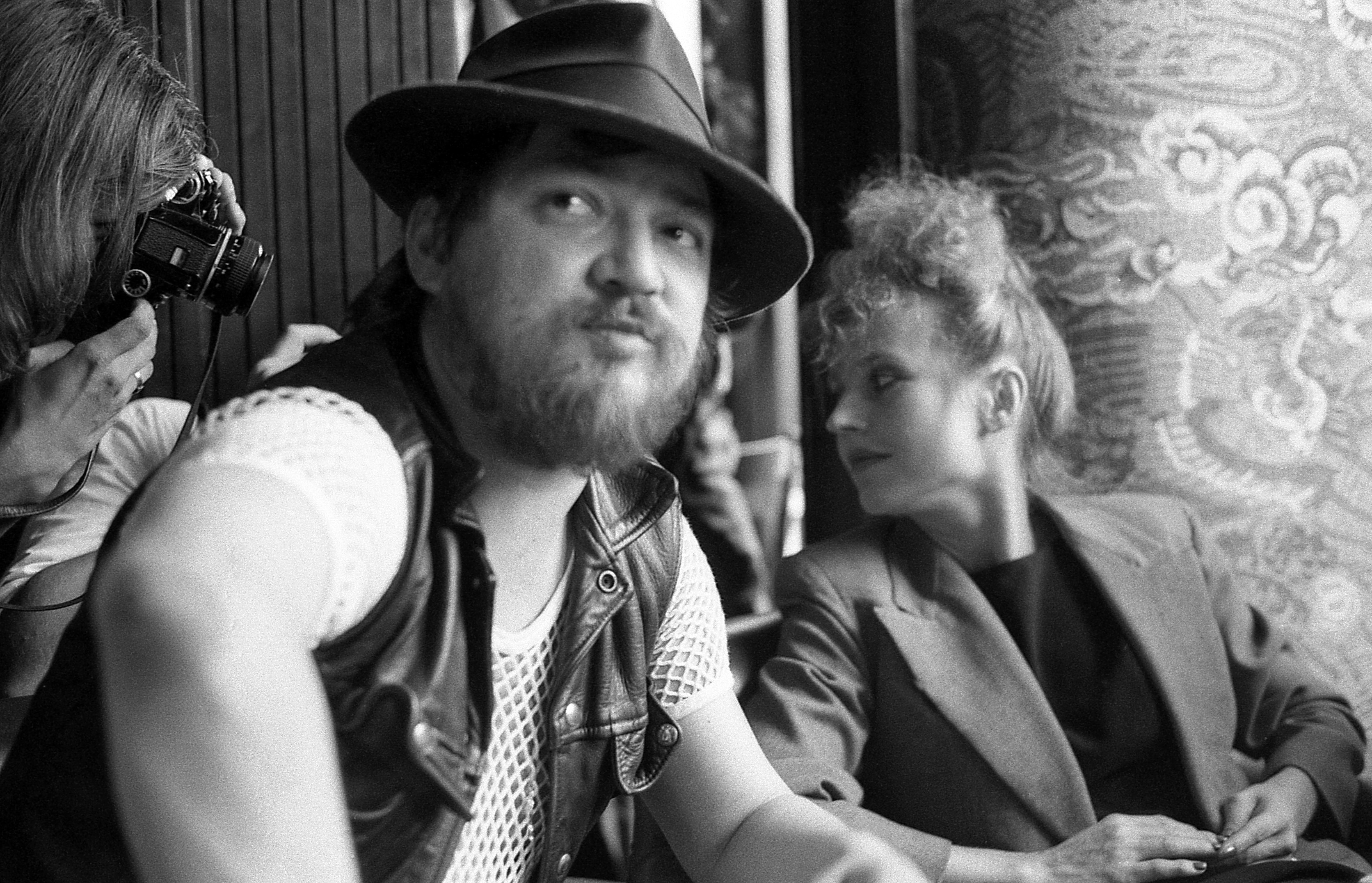 Photo en noir et blanc du réalisateur Rainer Maria Fassbinder et l'actrice Hanna Schygulla en arrière-plan